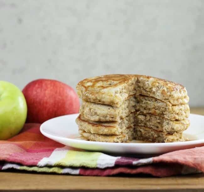 A side view of a stack of apple oatmeal pancakes with a slice taken out of the stack.