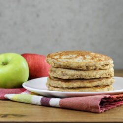 Looking at a side view of a stack of apple oatmeal pancakes on a white plate..