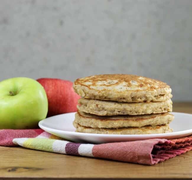 Looking at a side view of a stack of apple oatmeal pancakes on a white plate..