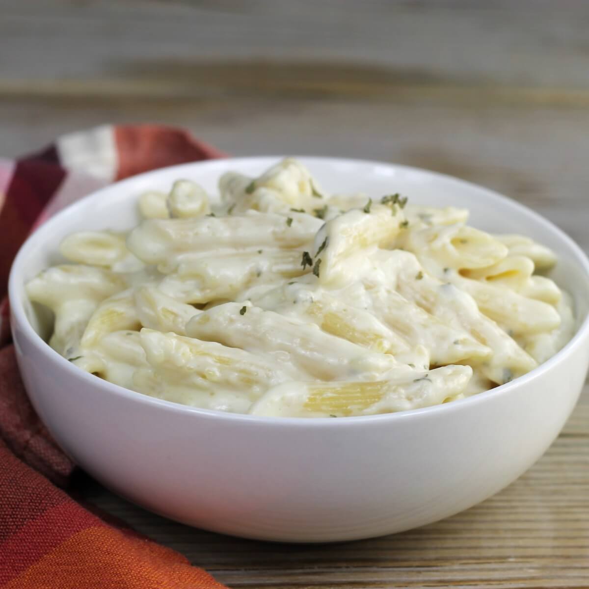 A side angle view of a white bowl of creamy pasta.