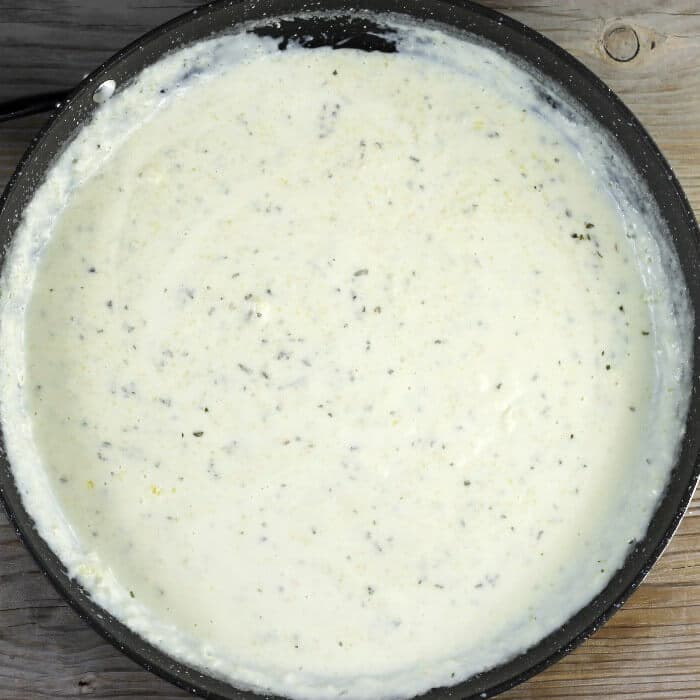 Looking down at a creamy sauce in a large skillet. 