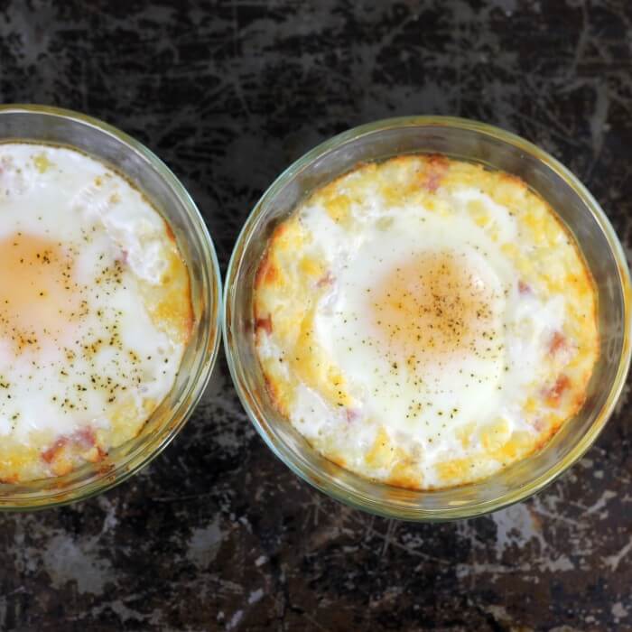 Looking down at a baking sheet with a couple of custard cups with baked mashed potatoes and eggs. 