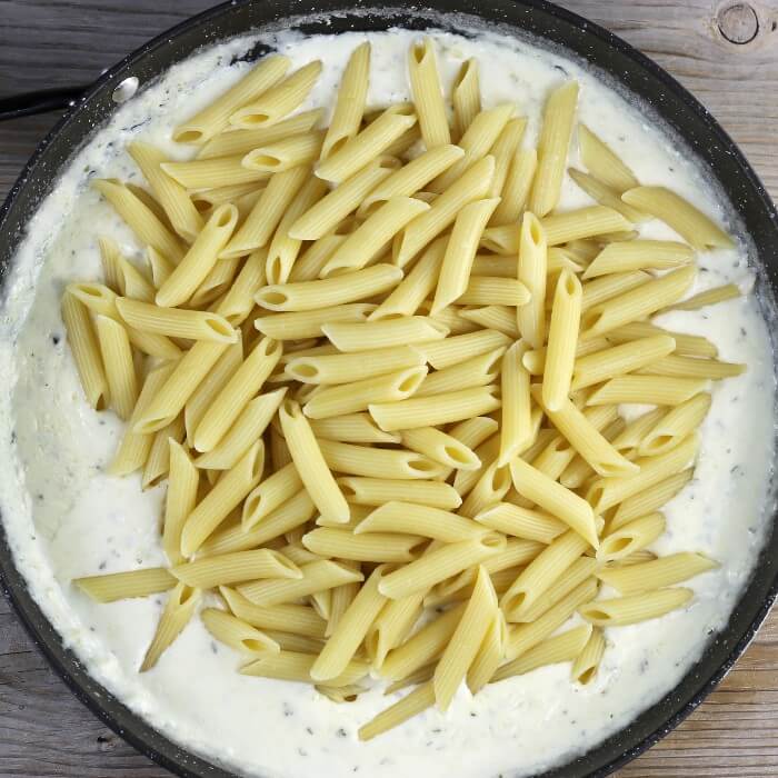Pasta is added to the white sauce.