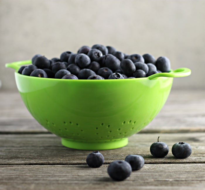 Green colander with blueberries.