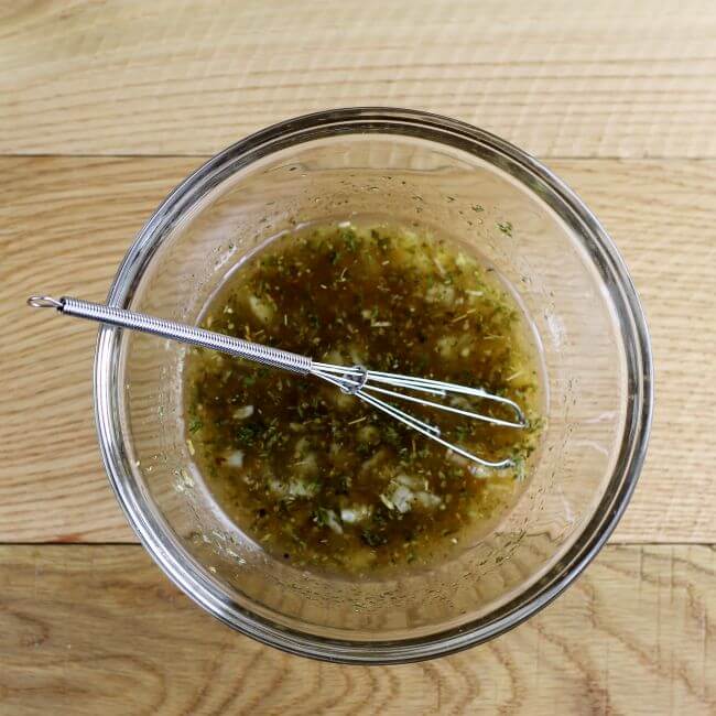 Marinade in a glass bowl with a whisk.