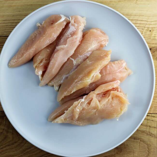 Raw chicken tenders on a gray plate.