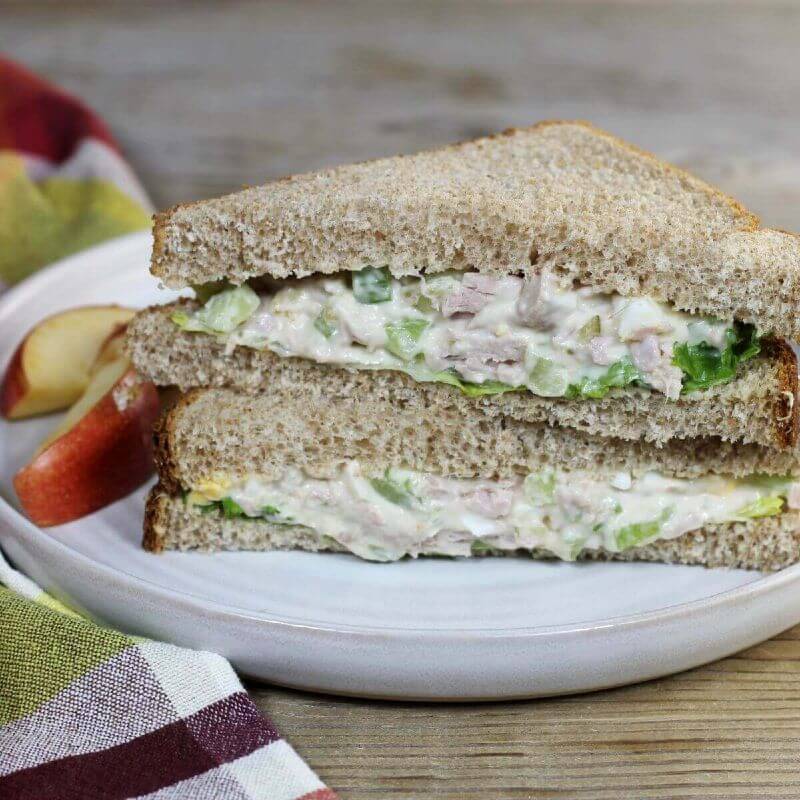 A side view of a tuna salad sandwich on a white plate.