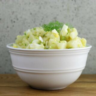 Side view of a white bowl with no-mayo potato salad.