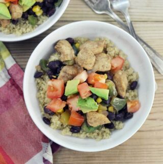 Looking down at white bowl with quinoa, chicken and vegetables.