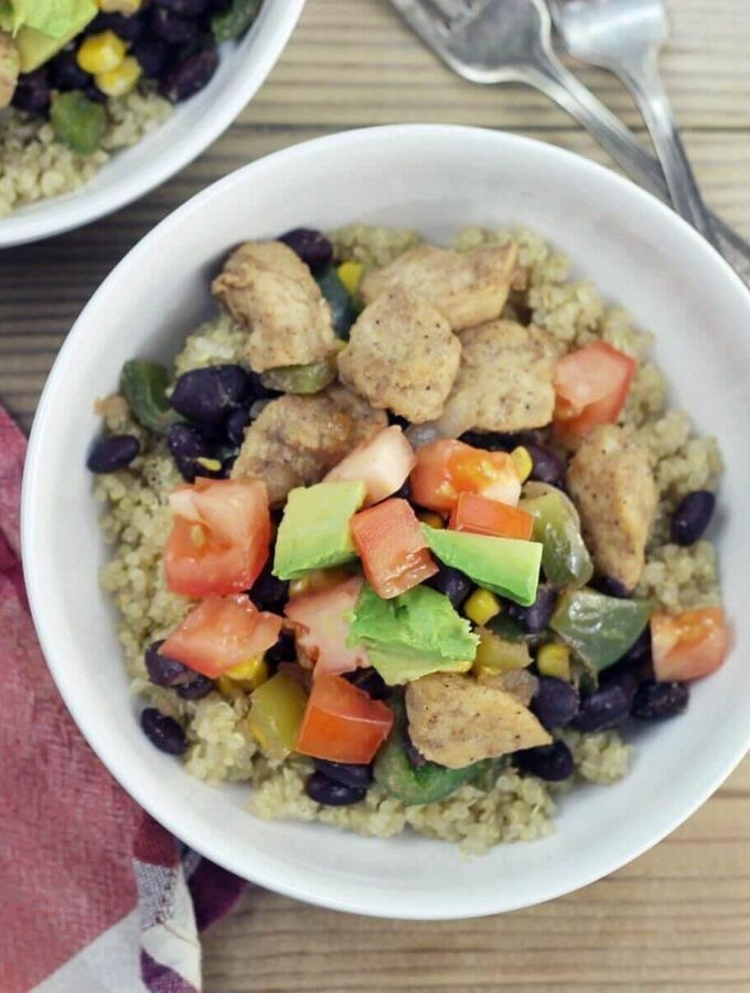 Looking down at white bowl with quinoa, chicken and vegetables.