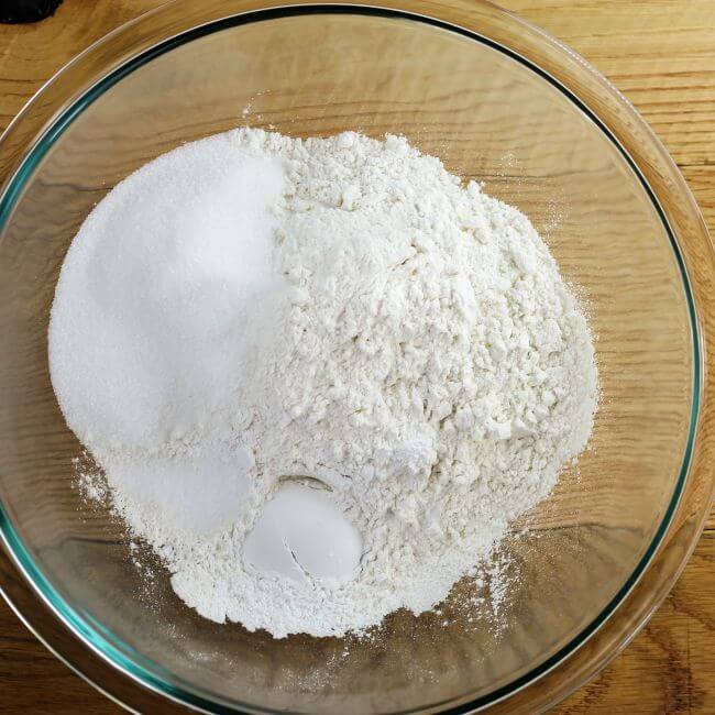 Flour, sugar, baking soda, and salt in a glass mixing bowl.