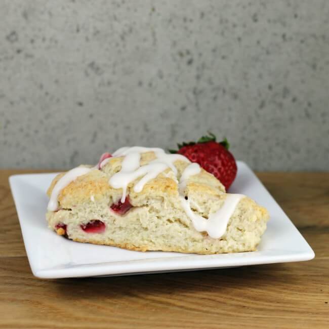 Side view of a strawberry scone on a white plate.