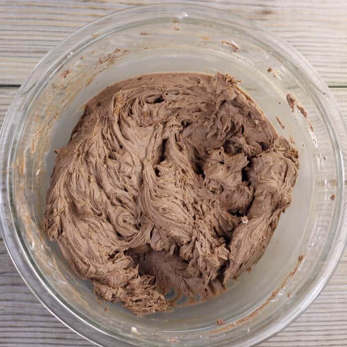 Looking down at chocolate frosting in a medium bowl.