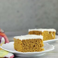 Side view of two pieces of easy pumpkin bars on white plates.