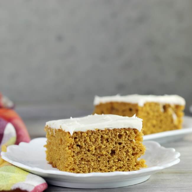 Side view of two pieces of easy pumpkin bars on white plates. 