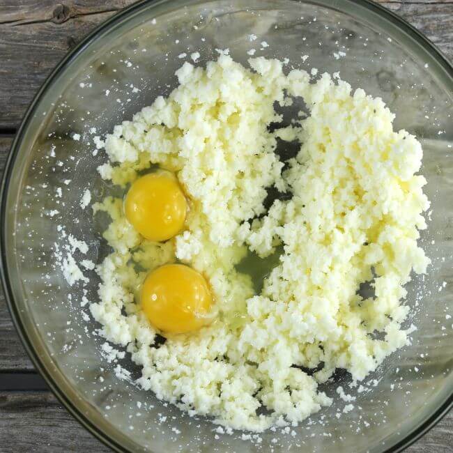 Eggs added to the sugar and butter batter in a glass bowl.