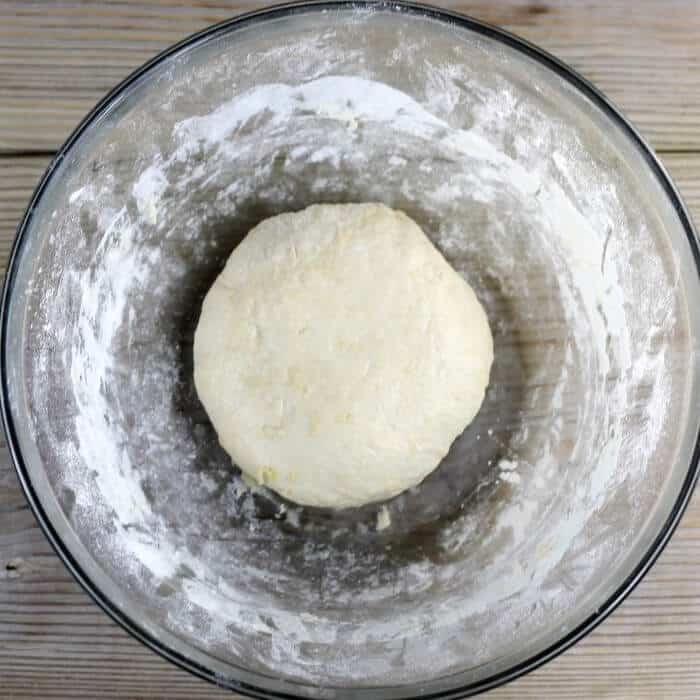 A ball of pizza dough in a glass bowl. 
