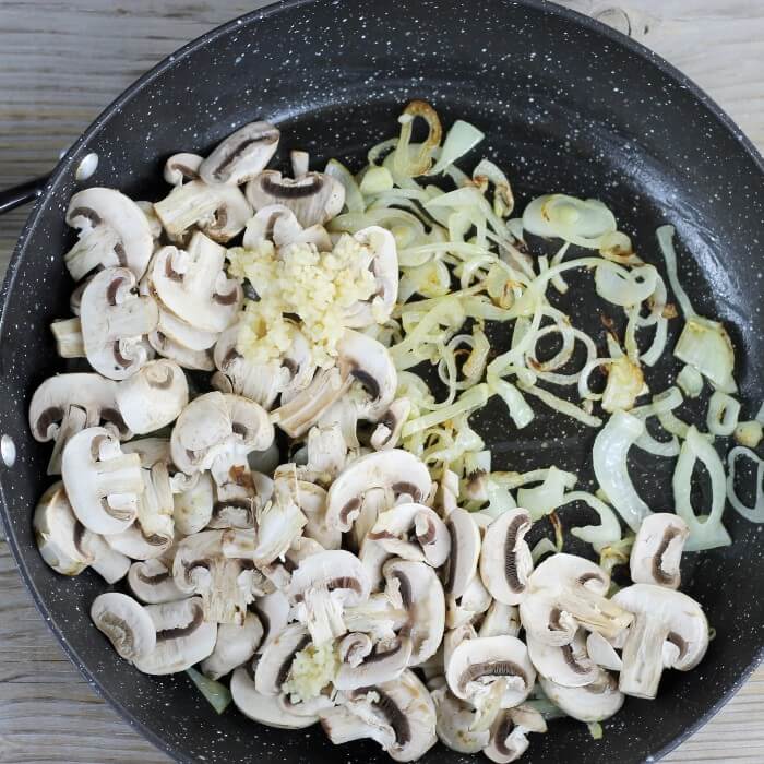 Mushrooms and garlic are added to the cooked onions.