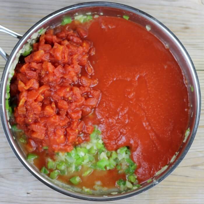 Diced tomatoes and tomato sauce are added to the cooked green pepper mixture.