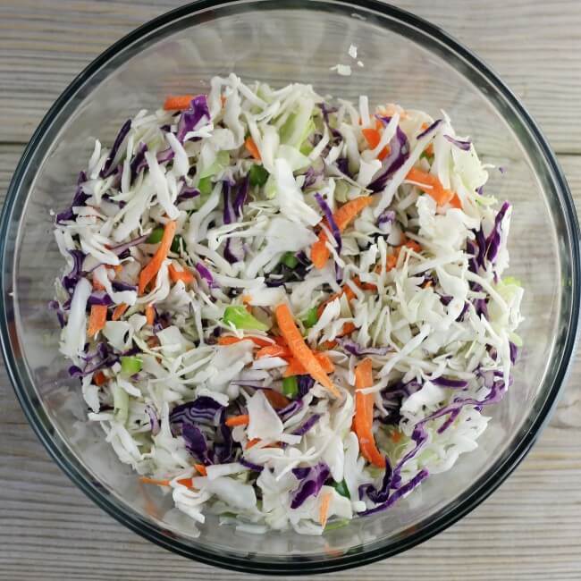 Green peppers, onions, and coleslaw mixture in a glass bowl.