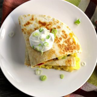 Breakfast quesadillas stuffed full of eggs, sausage, tomatoes, green peppers, onion, and cheddar cheese.
