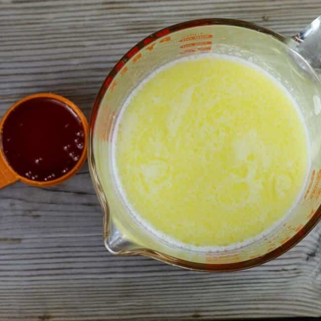 Milk and melted butter in a measuring cup with a cup of honey.