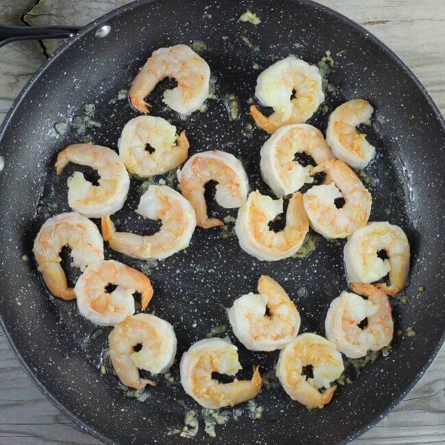 Shrimp are added to a large skillet.