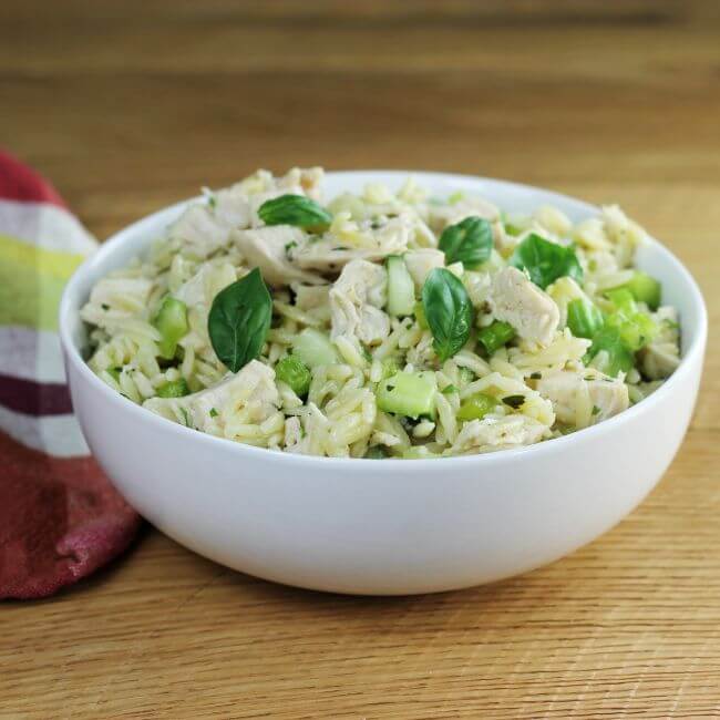 Looking at a side angle view of a white bowl with easy chicken orzo salad.