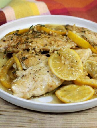 A side angle view of a plate with chicken tenders and lemon slices.