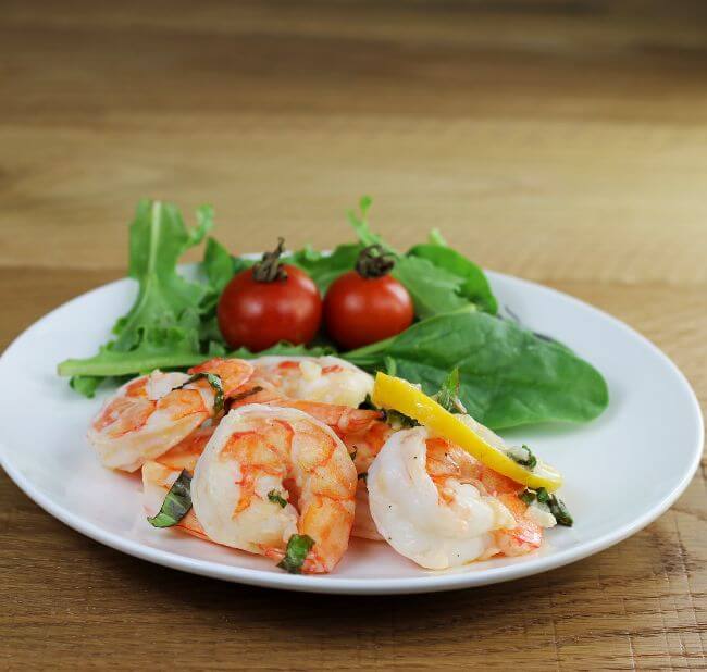 Shrimp and salad on a white plate.