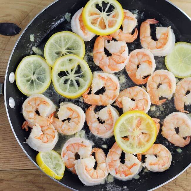 Shrimp with lemon slices in a skillet.