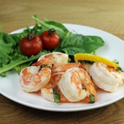 Side view of a plate with shrimp and lettuce salad.