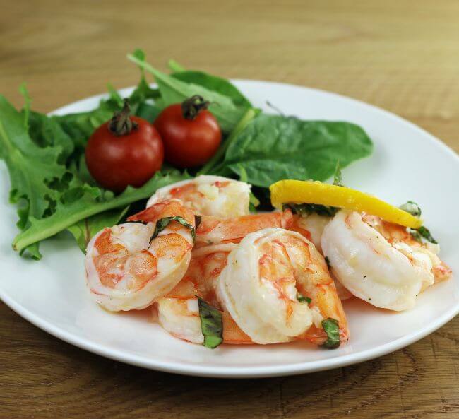 Side view of a plate with shrimp and lettuce salad. 