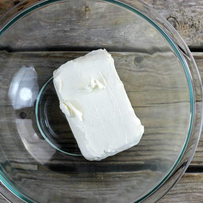 A block of cream cheese in a glass bowl.