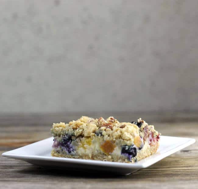 A piece of blueberry peach bars on a white plate.