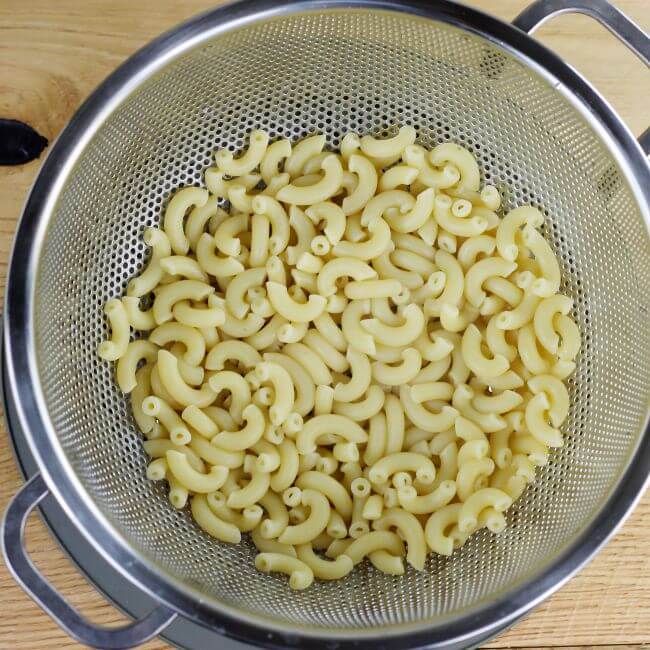 A colander with elbow macaroni.