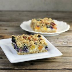 Two plates with blueberry peach bars. on a wooden table.