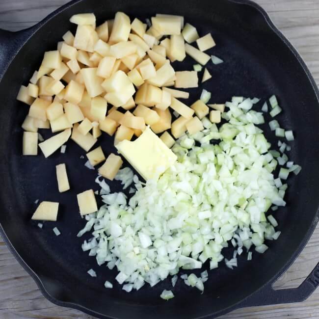 Onions, potatoes, celery, and butter are added to a large skillet.