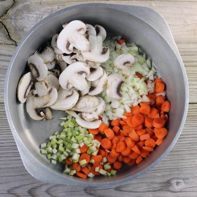 Vegetables are added to a Dutch oven to saute.