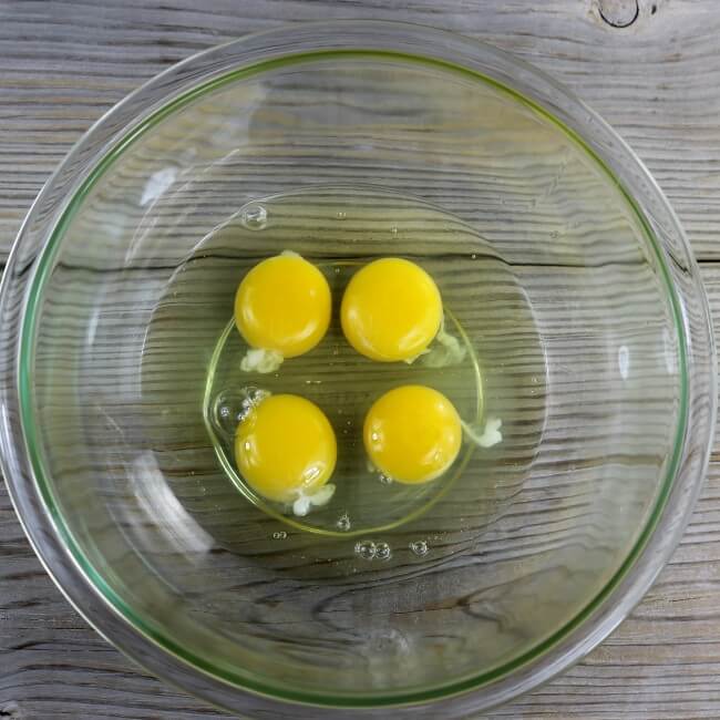 Four eggs in a glass mixing bowl.