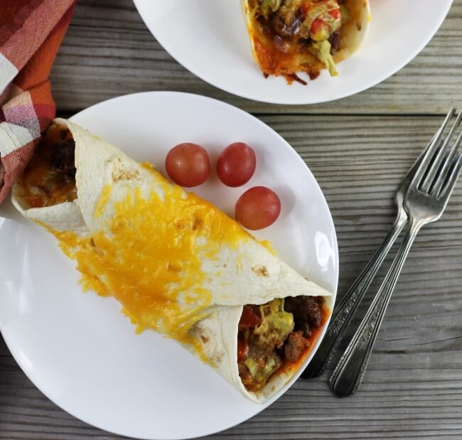 Looking down at a couple of white plate with easy bedf enchiladas.