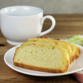 Looking at a side view of a plate with orange bread with a coffee mug in the background.