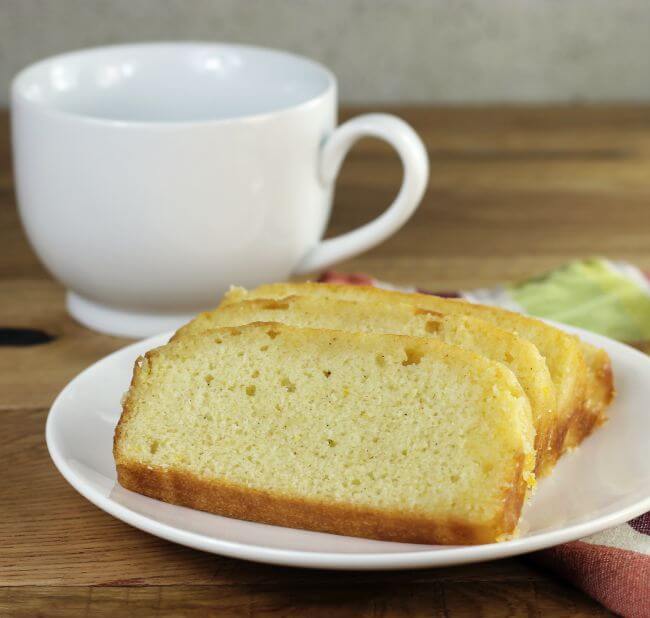 Looking at a side view of a plate with orange bread with a coffee mug in the background.