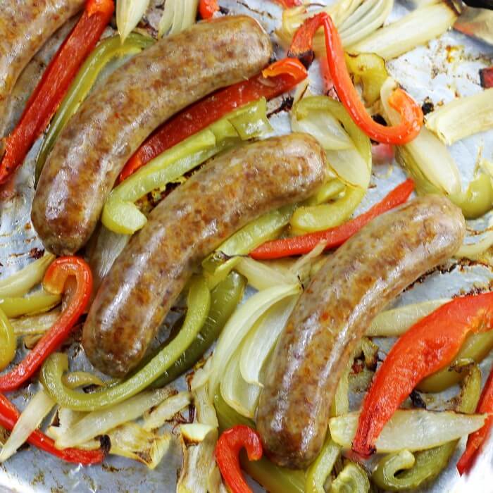 Baked Sausages along with onions and peppers on a baking pan.
