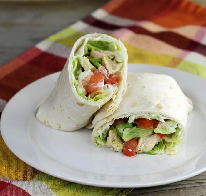 Looking a side view of a chicken wrap on a white plate.