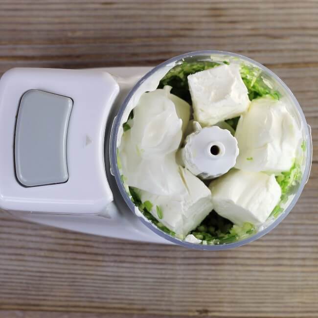 looking down at a food processor with cream cheese and sour cream.