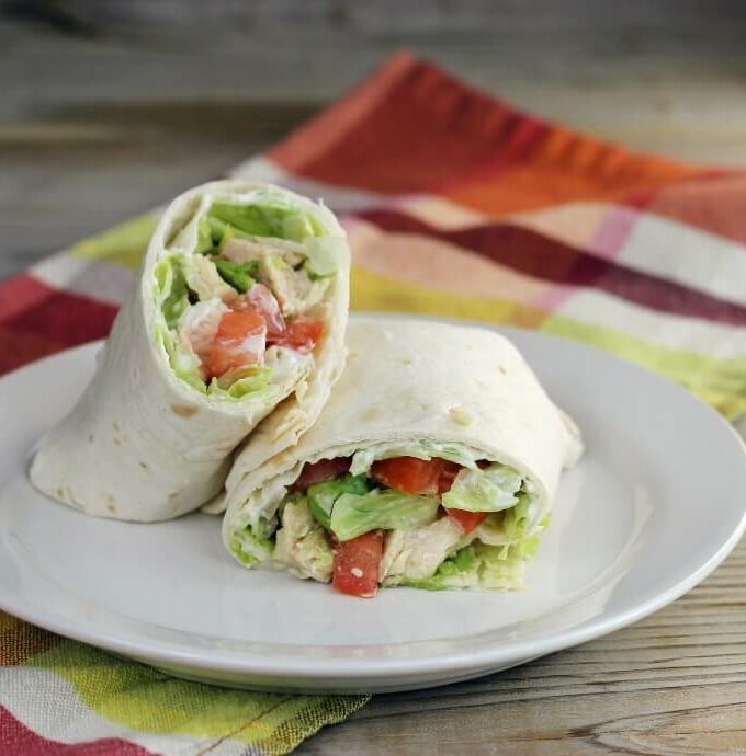 Side angle view of a wrap with chicken, tomato, and lettuce.