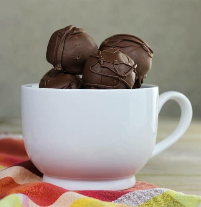 Side view of Chocolate brownie truffles in a white mug.