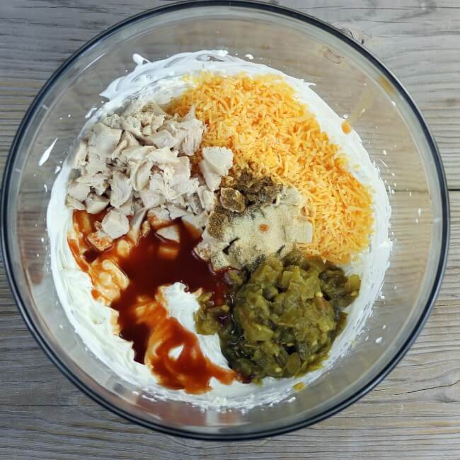 Chiles, chicken, enchilada sauce, cheese, and seasonings are added to the cream cheese mixture. 