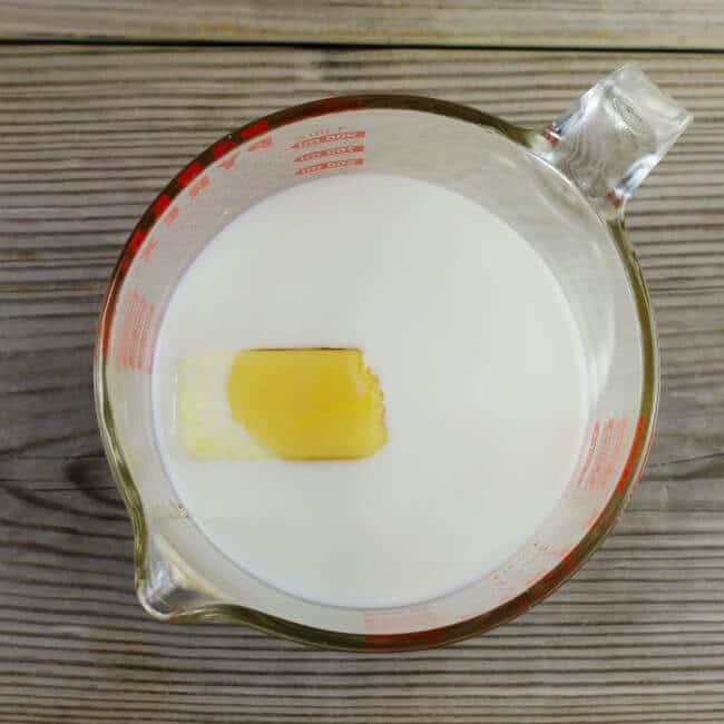 Milk, butter, and honey in a glass measuring cup.